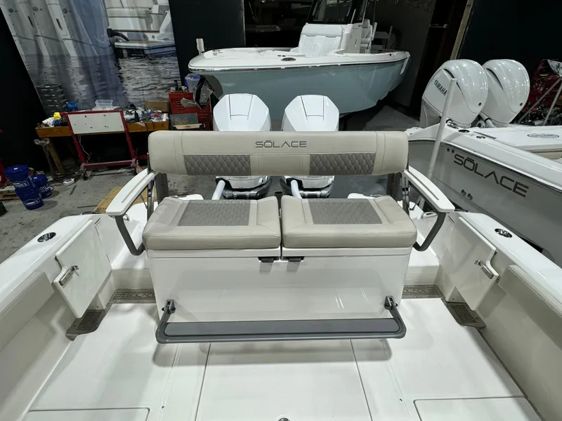 Slide: The Image of 2025 Solace 30 HCS boat interior with cushioned seating and dual outboard motors. - 14