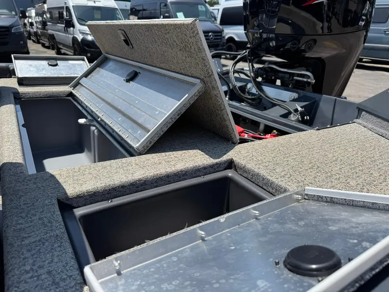 Slide: The Image of 2022 Tracker Pro Team 175 TF boat with open storage compartments and motor, parked outdoors. - 12