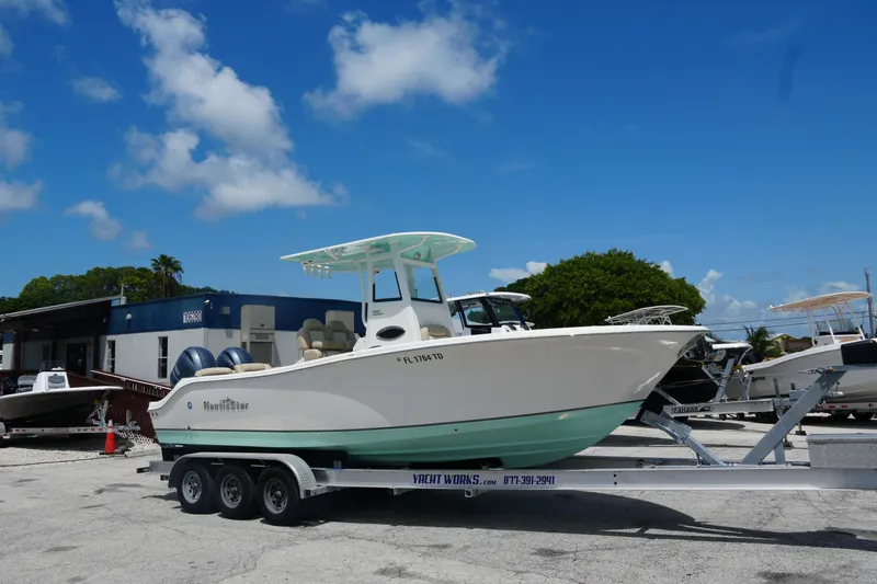 Slide: The Image of 2022 NauticStar 2602 boat on trailer under clear blue sky at dealership. - 2
