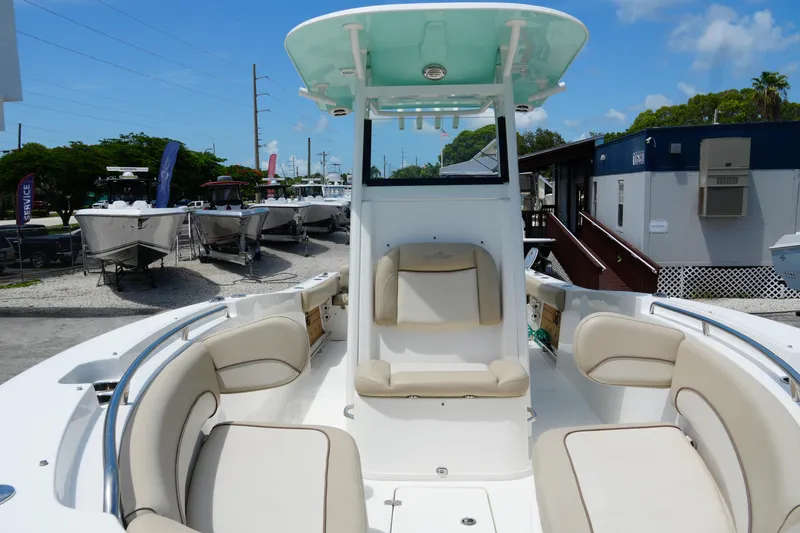 Slide: The Image of 2022 NauticStar 2602 boat interior with beige seating, docked outdoors under blue sky. - 21