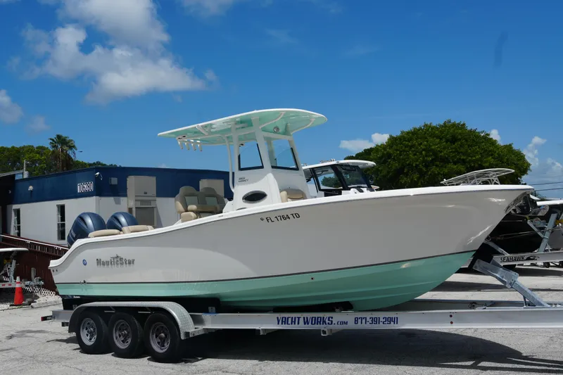 Slide: The Image of 2022 NauticStar 2602 boat on trailer, parked outdoors under blue sky. - 3