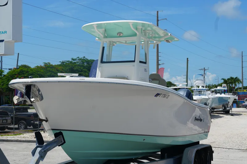 Slide: The Image of 2022 NauticStar 2602 boat on trailer, displayed outdoors under clear blue sky. - 6