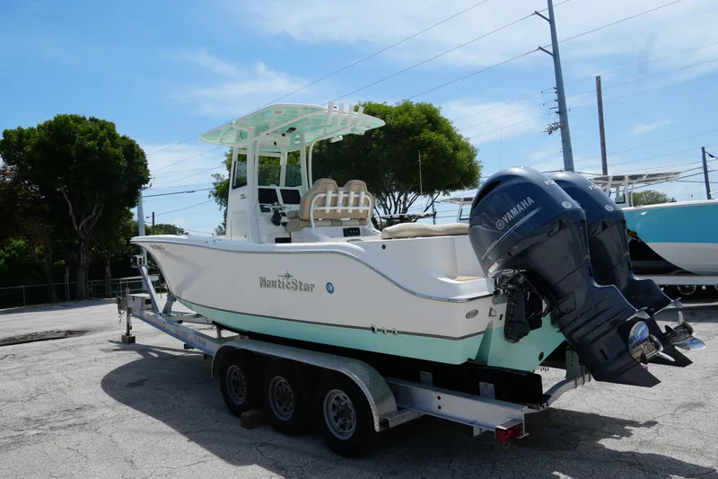 Slide: The Image of 2022 NauticStar 2602 boat on trailer with dual Yamaha engines, parked outdoors. - 7