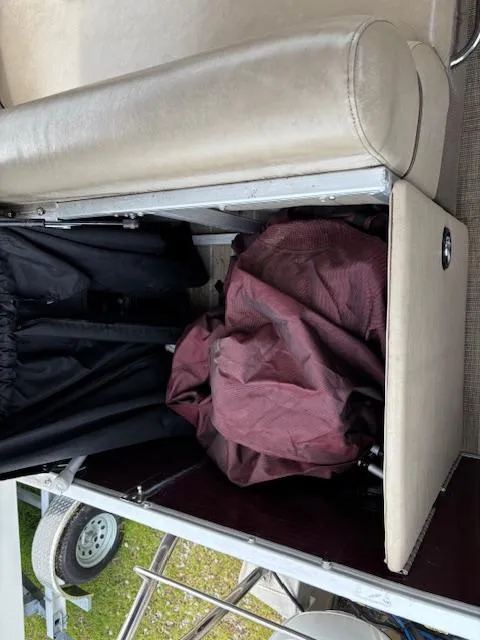 Slide: The Image of Open storage compartment on a 2021 Sweetwater 2186 boat, revealing fabric and gear. - 16