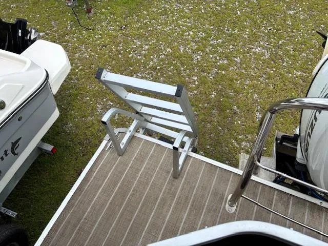 Slide: The Image of Aluminum boat ladder on Sweetwater 2186, 2021 model, with grassy background. - 19