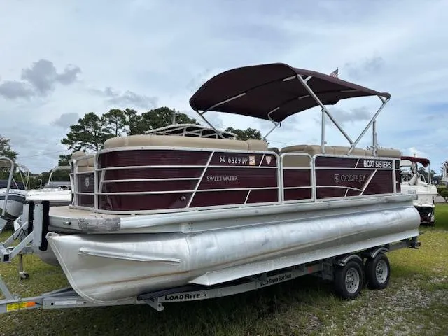Slide: The Image of 2021 Sweetwater 2186 pontoon boat on trailer, maroon and silver design, parked outdoors. - 7