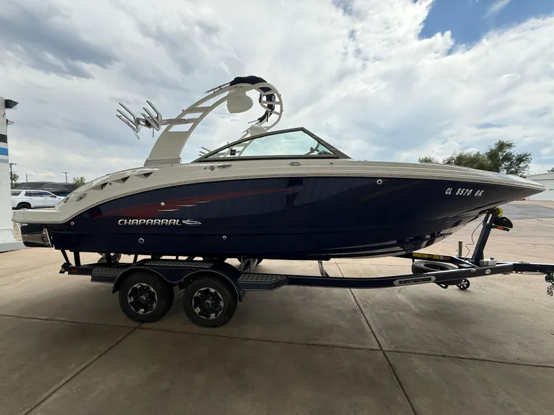 Slide: The Image of 2018 Chaparral 244 Sunesta Surf boat on trailer, parked outdoors under cloudy sky. - 4