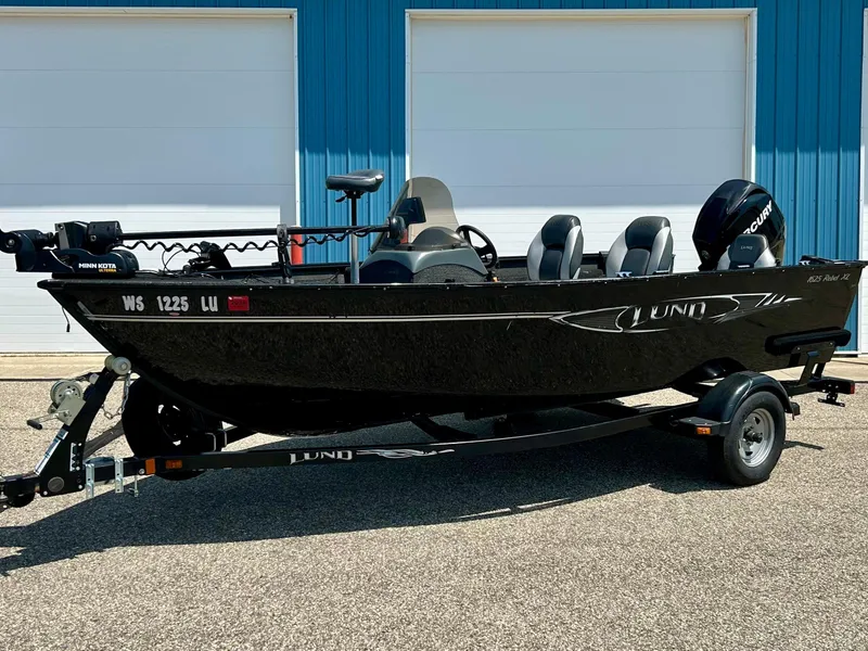Slide: The Image of 2014 Lund 1625 Rebel XL SS fishing boat on trailer, parked outside blue building. - 33