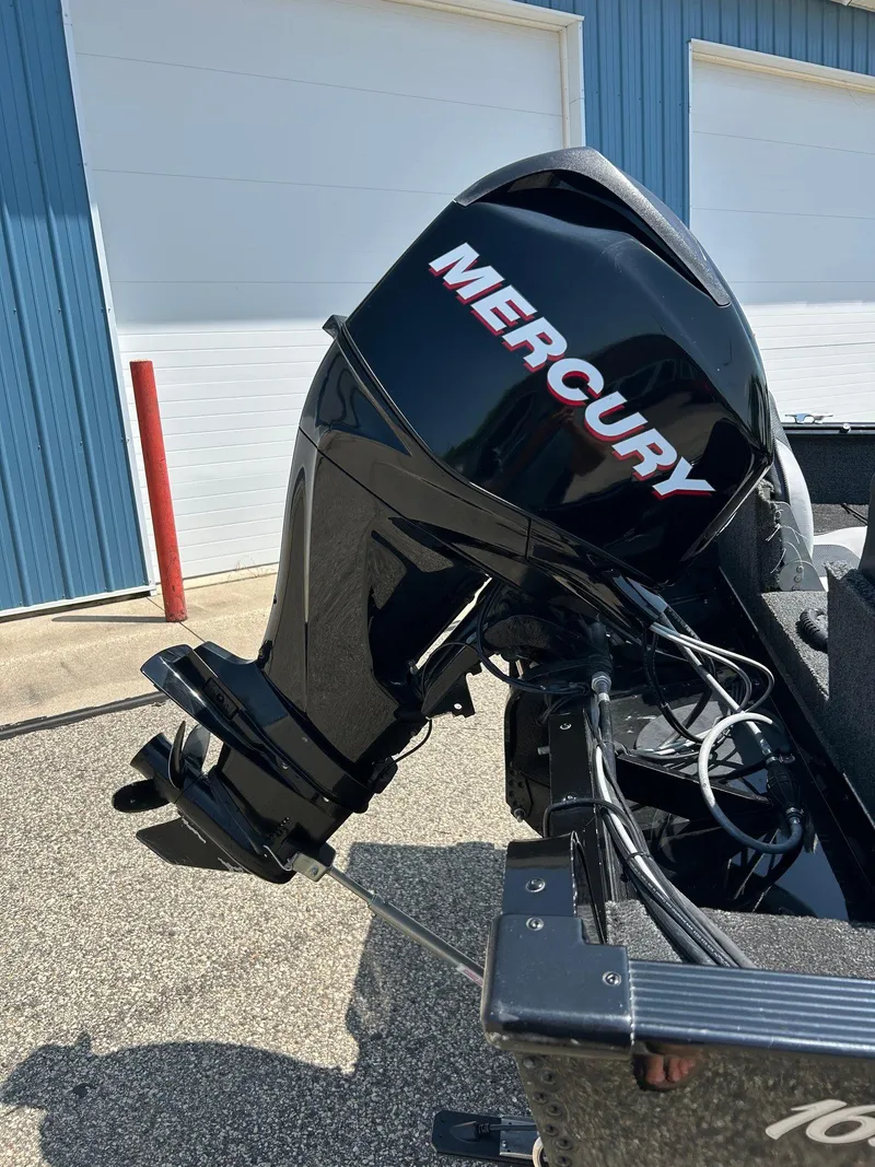 Slide: The Image of 2014 Lund 1625 Rebel XL SS with Mercury outboard motor, parked near blue building. - 9