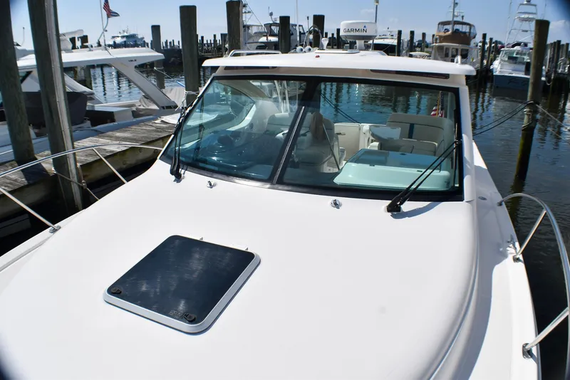 Slide: The Image of 2013 Tiara Yachts 3100 Open docked at marina, showcasing sleek design and spacious deck. - 18