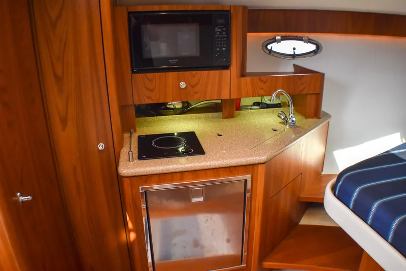 Slide: The Image of 2013 Tiara Yachts 3100 Open interior kitchen with microwave, sink, and stove. - 31