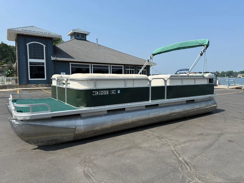 The Image of 1998 Bennington 22 pontoon boat parked near a waterfront building. - 0