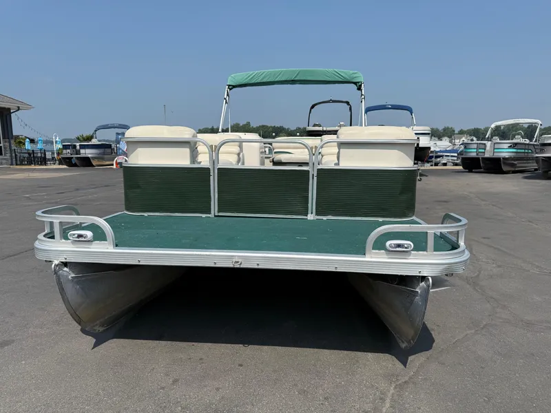 Slide: The Image of 1998 Bennington 22 pontoon boat with green canopy and seating, parked on asphalt. - 1