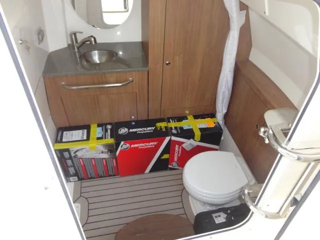 Slide: The Image of 2021 Boston Whaler 350 Outrage cabin with sink, toilet, and Mercury boxes on the floor. - 20