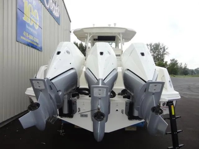 Slide: The Image of 2021 Boston Whaler 350 Outrage with triple outboard engines, docked near a building. - 8