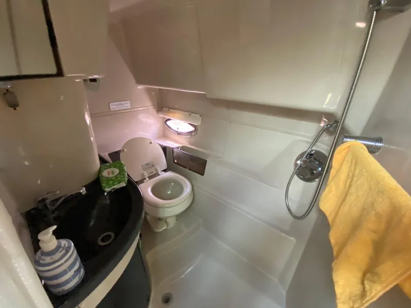Slide: The Image of Compact bathroom in a 2006 Doral 365 boat, featuring a toilet, sink, and shower. - 38