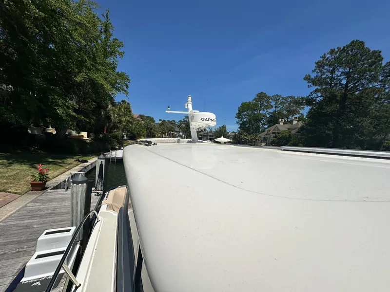 Slide: The Image of 2022 Back Cove 372 boat docked, surrounded by trees and clear blue sky. - 10