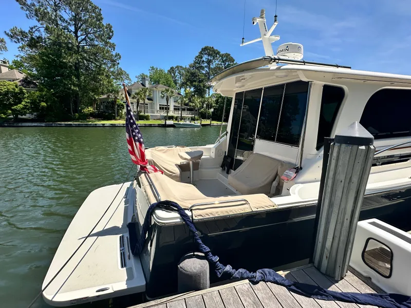 Slide: The Image of 2022 Back Cove 372 yacht docked by a serene waterfront with lush greenery. - 18