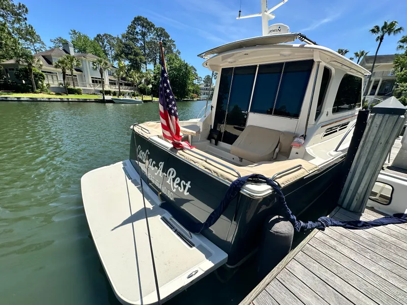 Slide: The Image of 2022 Back Cove 372 yacht docked, displaying American flag, surrounded by waterfront homes. - 2