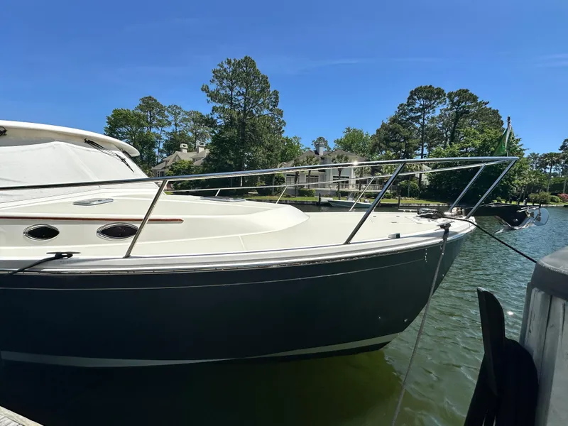 Slide: The Image of 2022 Back Cove 372 boat docked on a sunny day, surrounded by trees and houses. - 20