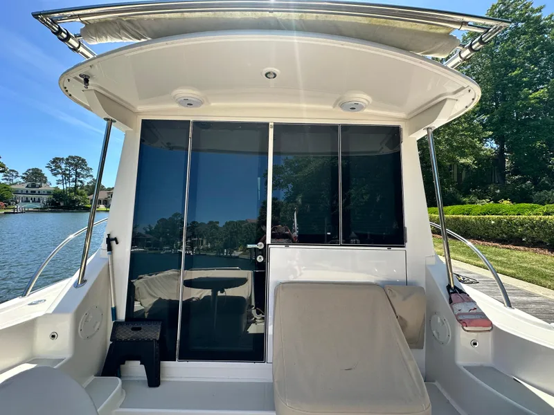 Slide: The Image of 2022 Back Cove 372 boat with sliding glass doors, docked by a scenic waterfront. - 23