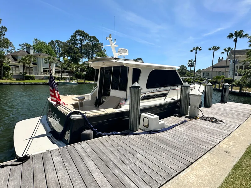 Slide: The Image of 2022 Back Cove 372 yacht docked by waterfront homes, clear sky, and lush greenery. - 3