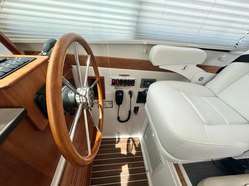 Slide: The Image of 2022 Back Cove 372 helm with wooden steering wheel and white captain's chair. - 31