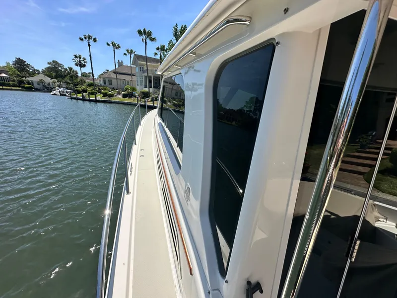 Slide: The Image of 2022 Back Cove 372 yacht docked by waterfront homes and palm trees. - 41