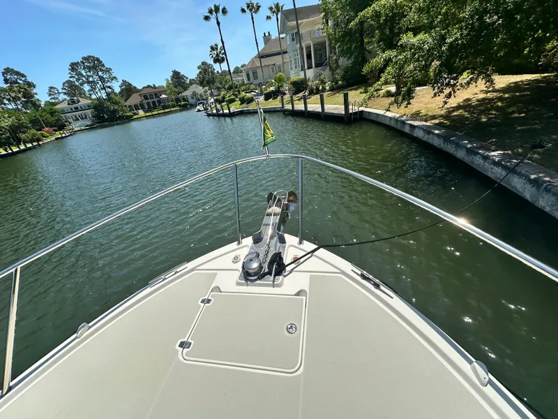 Slide: The Image of Bow view of 2022 Back Cove 372 yacht navigating a scenic residential waterway. - 6