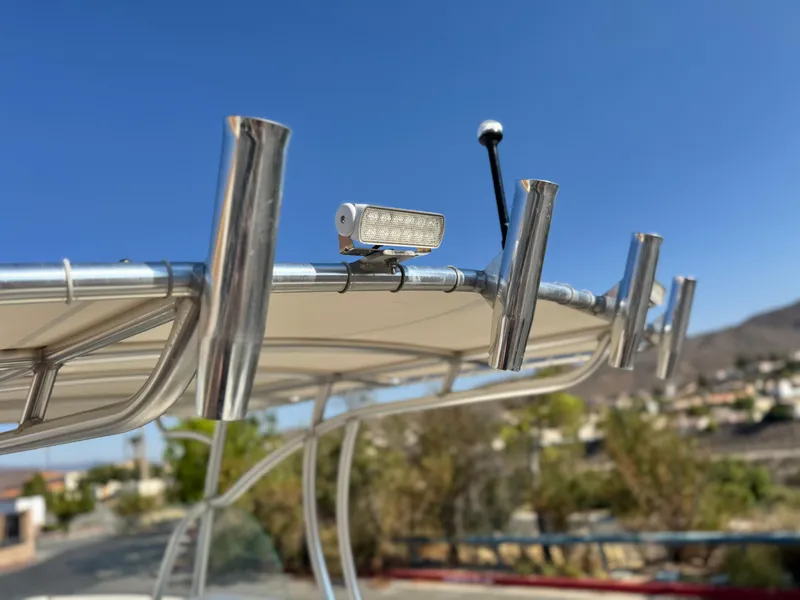 Slide: The Image of 2021 Sailfish 242 CC boat with rod holders and light against clear blue sky. - 16