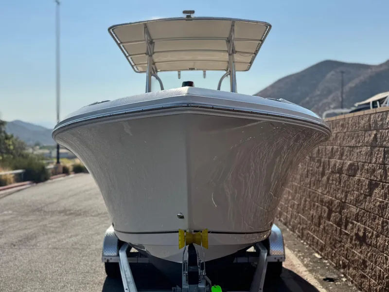 Slide: The Image of 2021 Sailfish 242 CC boat on trailer, parked near a brick wall with mountains in background. - 2