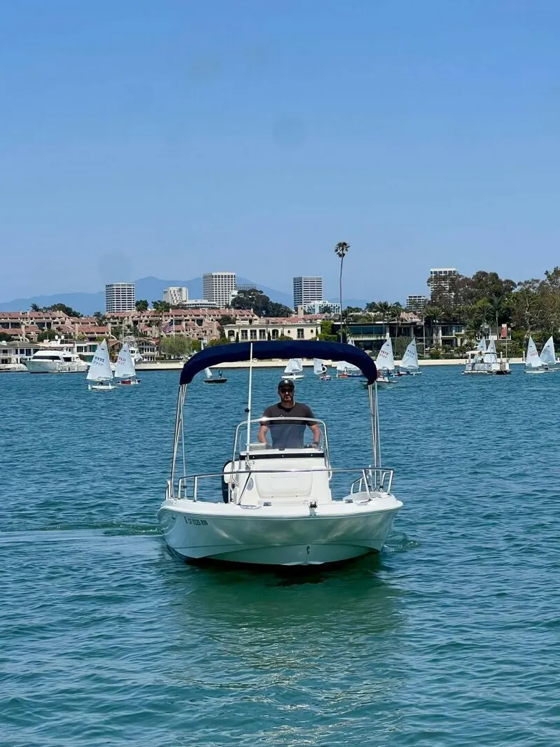 Slide: The Image of 2016 Boston Whaler 180 Dauntless cruising on a sunny day with sailboats in the background. - 12