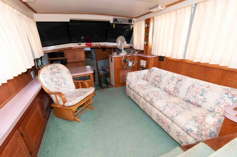 Slide: The Image of 1988 Mainship 36 Double Cabin interior with floral sofa, wooden chair, and helm station. - 6