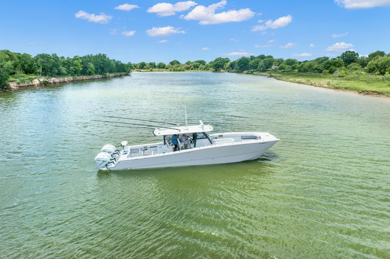 Slide: The Image of 2022 Freeman 47 boat cruising on a scenic river under a clear blue sky. - 27