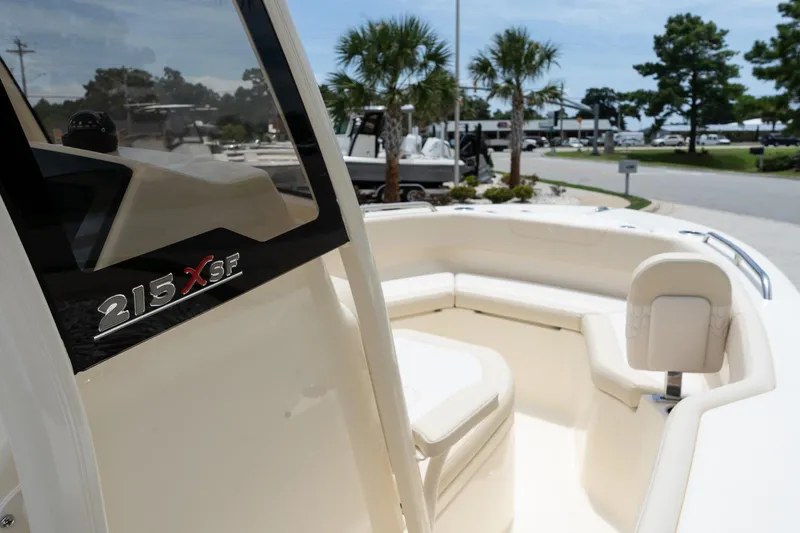 Slide: The Image of 2026 Scout 215 XSF boat interior with seating, palm trees in the background. - 12