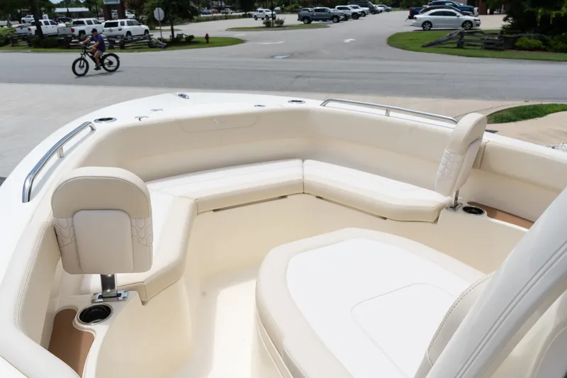 Slide: The Image of 2026 Scout 215 XSF boat interior with cream seating and cup holders, parked near a road. - 13