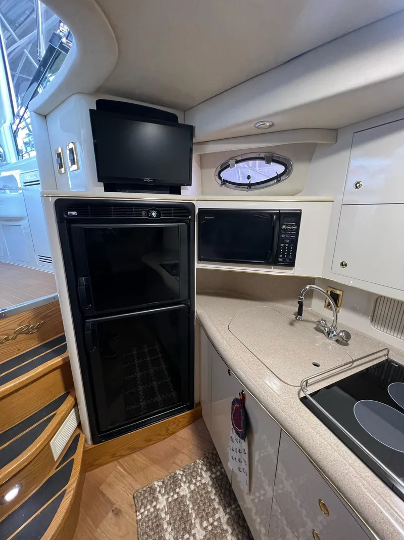 Slide: The Image of 1997 Sea Ray 400 Sundancer kitchen with stove, microwave, and white cabinetry. - 19