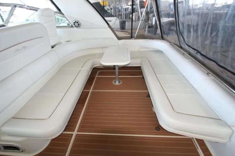 Slide: The Image of 1997 Sea Ray 400 Sundancer interior with white seating, nautical pillows, and a sleek table. - 32