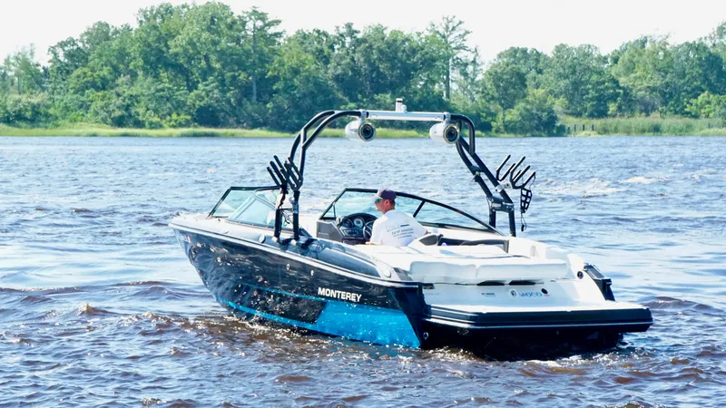 The Image of 2016 Monterey 238 Super Sport boat cruising on a lake with lush green trees. - 1