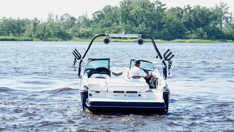 Slide: The Image of 2016 Monterey 238 Super Sport boat cruising on a lake with lush green shoreline. - 5