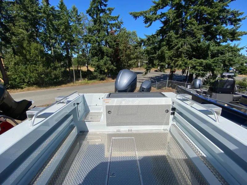 Slide: The Image of 2025 Hewescraft 240 Ocean Pro ET HT boat deck with outboard motors, surrounded by trees. - 10