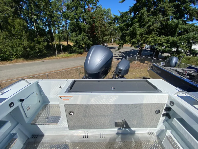 Slide: The Image of 2025 Hewescraft 240 Ocean Pro ET HT boat deck with outboard motors, surrounded by trees. - 11