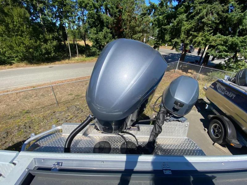 Slide: The Image of 2025 Hewescraft 240 Ocean Pro ET HT boat engines, parked outdoors with trees in the background. - 12