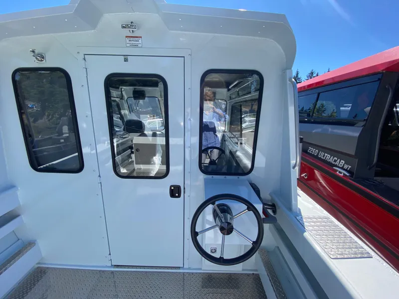 Slide: The Image of 2025 Hewescraft 240 Ocean Pro ET HT boat interior with steering wheel and cabin door. - 6