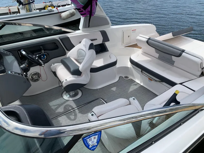 Slide: The Image of 2019 Chaparral 257 SSX boat interior with luxurious seating and steering wheel, docked by water. - 23