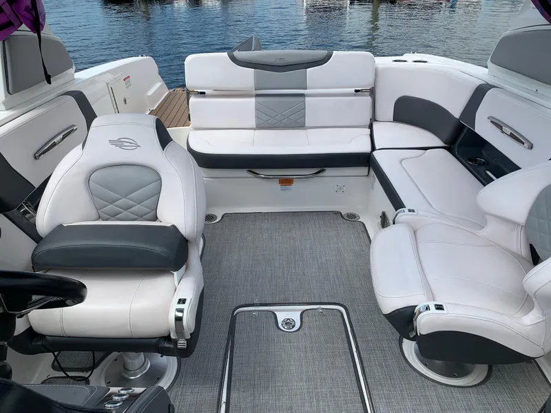Slide: The Image of 2019 Chaparral 257 SSX boat interior with white and gray seating, docked by the water. - 35