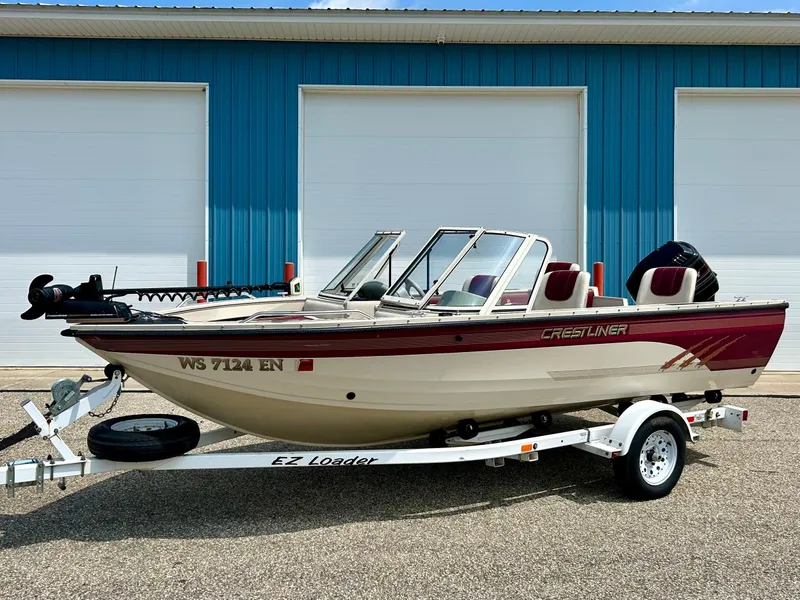 Slide: The Image of 1997 Crestliner 1650 Sportfish boat on EZ Loader trailer, parked outside blue building. - 8