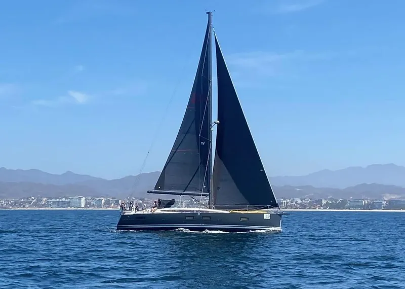 Slide: The Image of 2018 Jeanneau 54 sailboat cruising on open water with mountains in the background. - 2