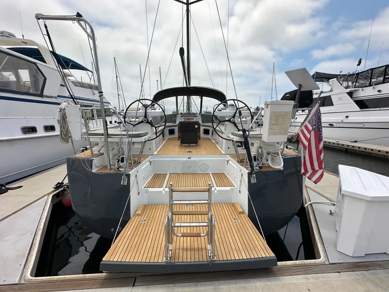 Slide: The Image of 2018 Jeanneau 54 yacht docked, featuring dual steering wheels and teak deck. - 21