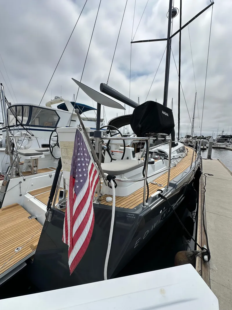 Slide: The Image of 2018 Jeanneau 54 yacht docked with American flag, featuring sleek design and wooden deck. - 23